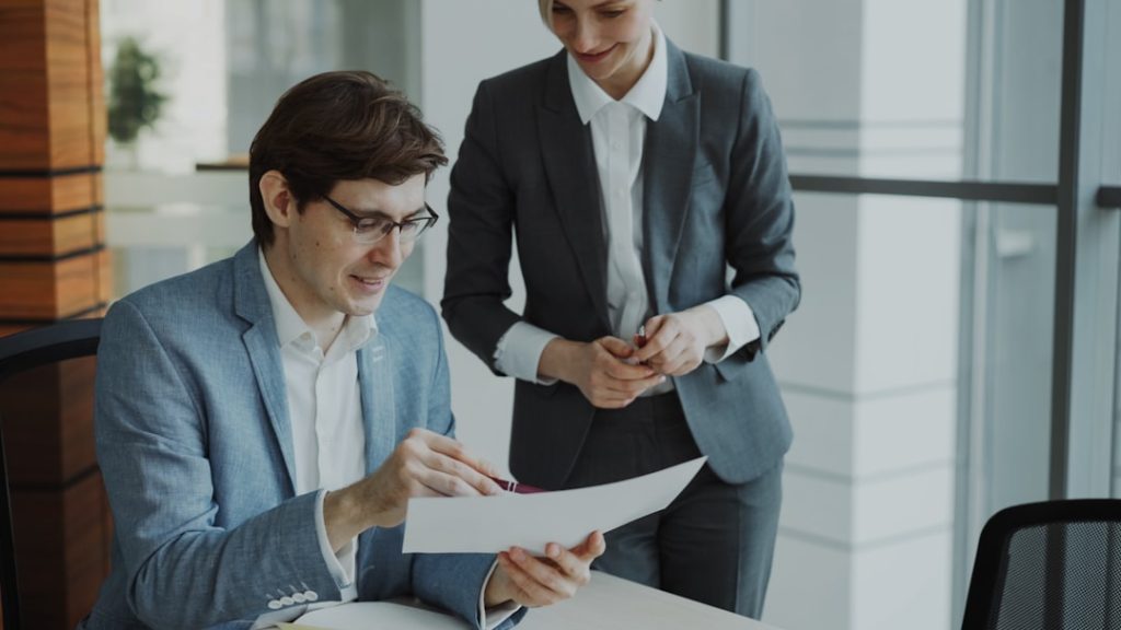 The Art of Drawing Readers In: Your attractive post title goes here Two business colleagues discussing reports in modern office indoors. Businessman sitting at the table talking his female partner